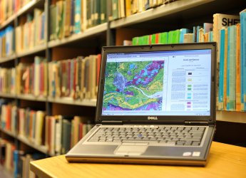 Bookshelf in library with laptop in foreground